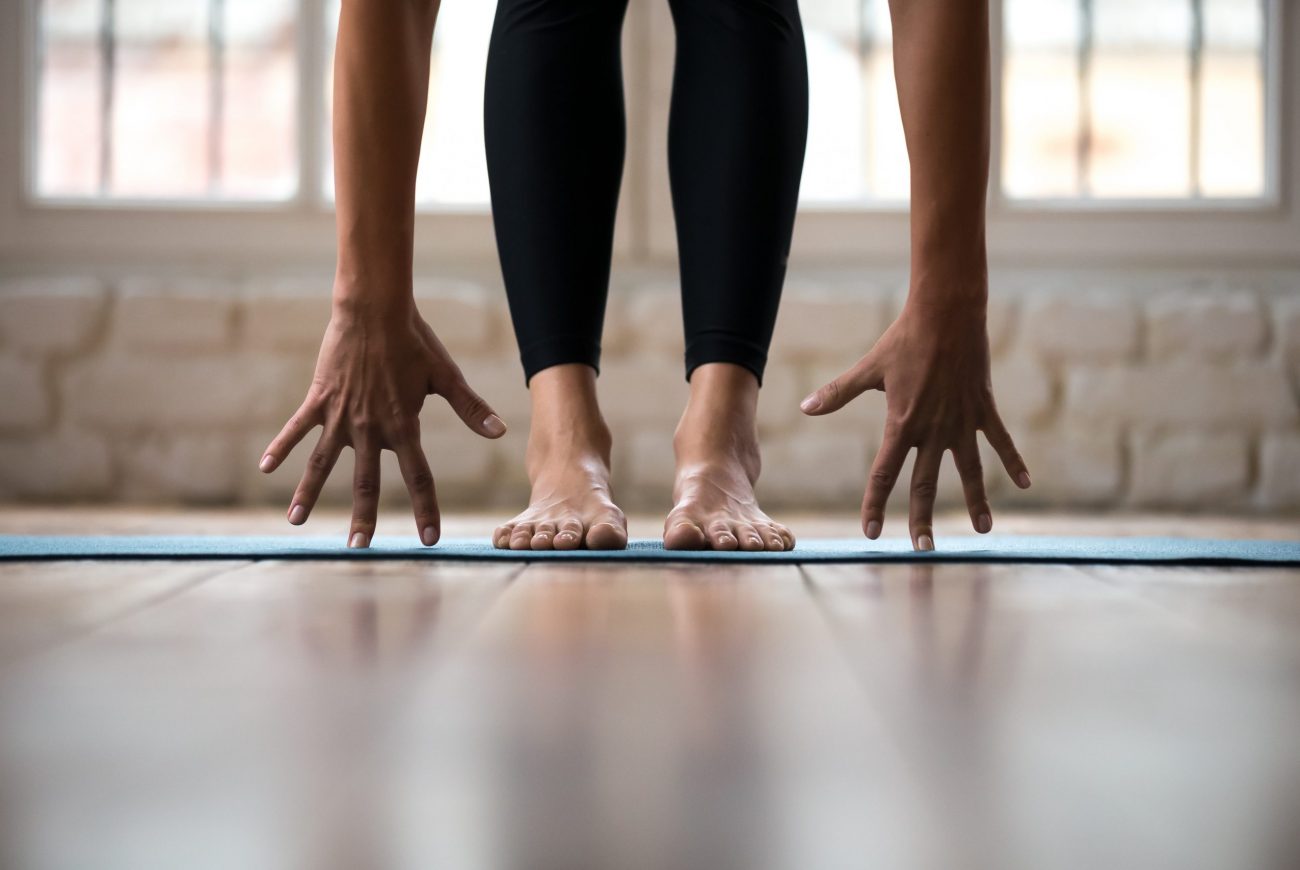 Sporty yogi woman practicing yoga, doing bend exercise, standing Sporty yogi woman practicing yoga, doing bend exercise, standing pose, working out, wearing sportswear, black pants, indoor close up, yoga studio